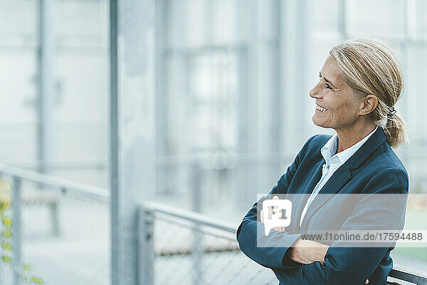 Happy businesswoman with arms crossed in office