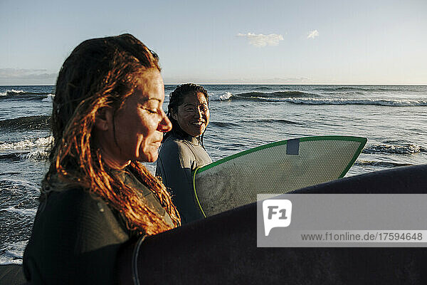 Smiling woman looking at surfer with surfboard at beach  Gran Canaria  Canary Islands