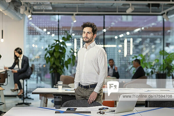 Thoughtful businessman standing in coworking space