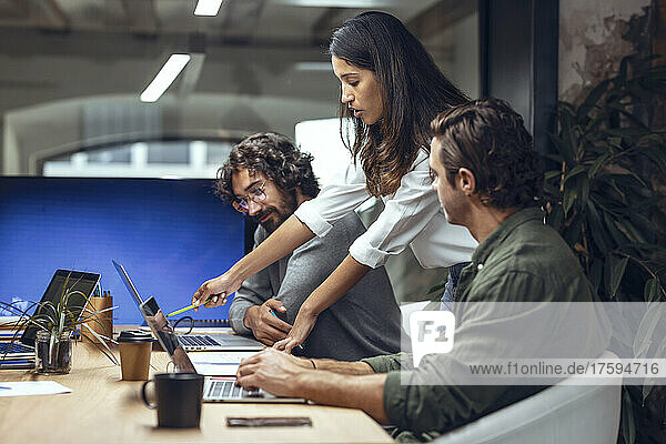 Businesswoman explaining business strategy to colleagues on laptop in meeting at office