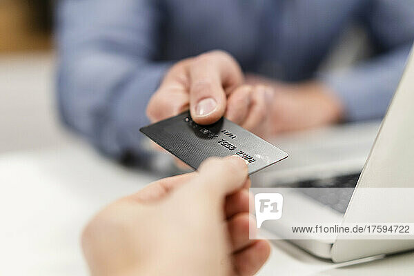 Colleagues holding credit card by laptop in office