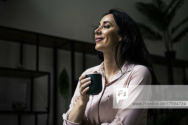 Smiling businesswoman having coffee in office