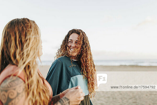 Smiling woman talking with friend at beach