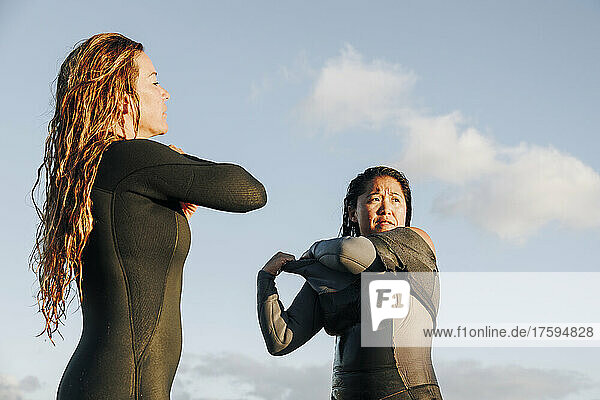 Female surfers removing wetsuit after surfing