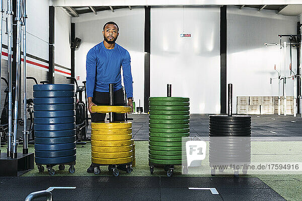 Young athlete standing near weight plates in gym