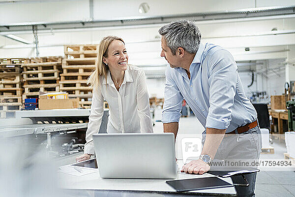 Geschäftsmann und Geschäftsfrau schauen einander an und diskutieren in der Fabrik