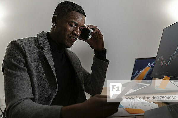 Young businessman talking on mobile phone at home office working late night
