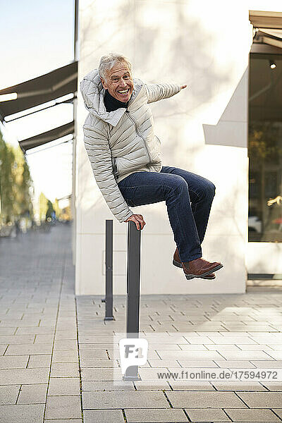 Playful elderly man jumping on footpath