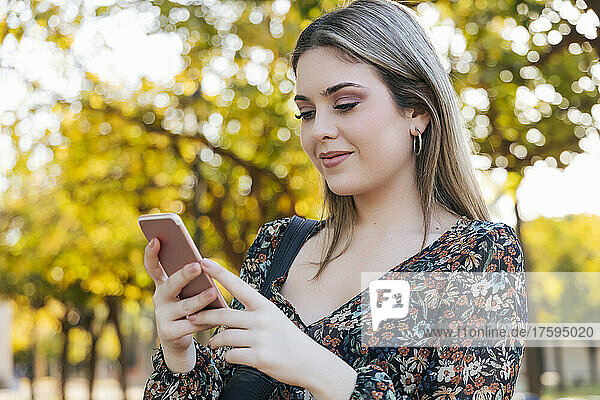 Smiling woman using smart phone in park