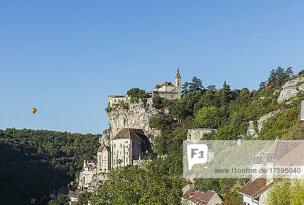 Frankreich  Lot  Rocamadour  Blick auf die Stadt an den Klippen mit Heißluftballon im Hintergrund