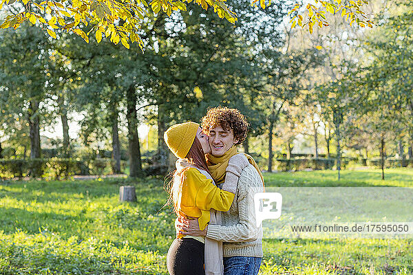 Woman kissing boyfriend on cheek at autumn park