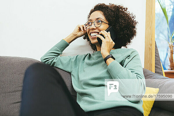 Happy woman talking on smart phone on sofa