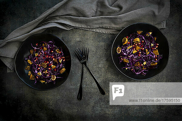 Studio shot of two bowls of vegan salad with red cabbage  pomegranate seeds  dried figs and walnuts