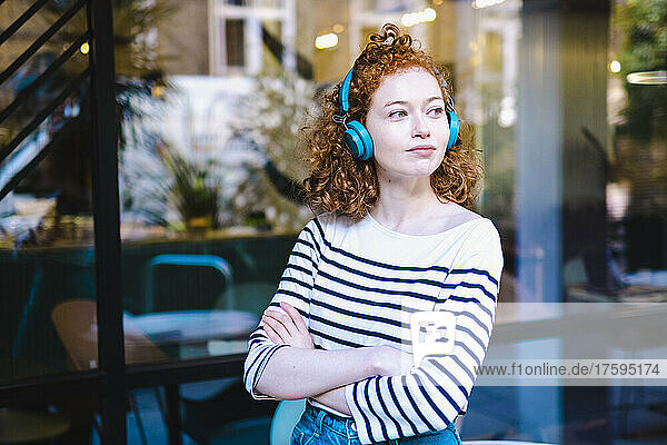 Young woman with arms crossed outside cafe