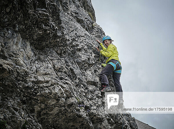 Smiling woman climbing rocky mountain