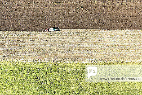 Drone view of tractor plowing field on sunny day