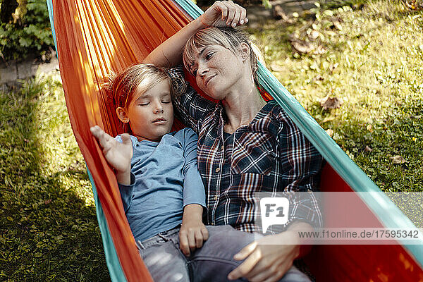 Mother looking at son sleeping in hammock