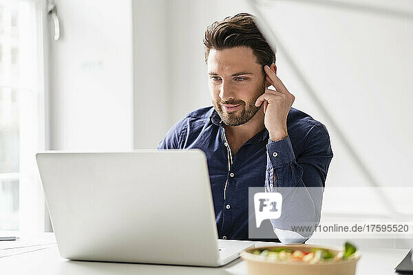 Konzentrierter Geschäftsmann arbeitet am Laptop am Schreibtisch im Büro