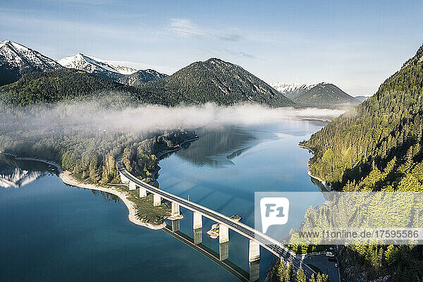 Sylvenstein Dam and bridge surrounded by morning mist in winter  Sylvensteinsee  Lenggries  Bavaria  Germany