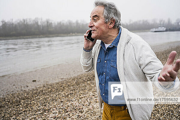 Senior man talking on smart phone at beach