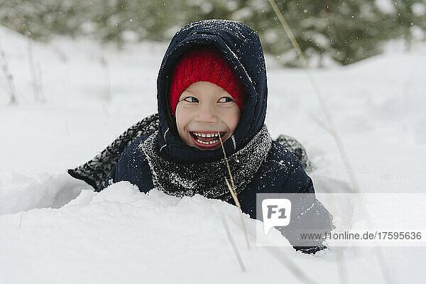 Happy boy playing in snow at forest