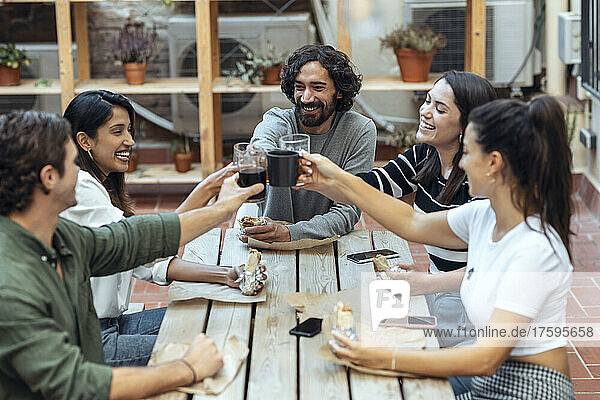 Happy businessmen and businesswomen toasting drinks at cafeteria