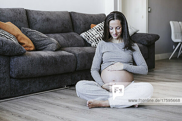 Smiling pregnant woman sitting on floor at home