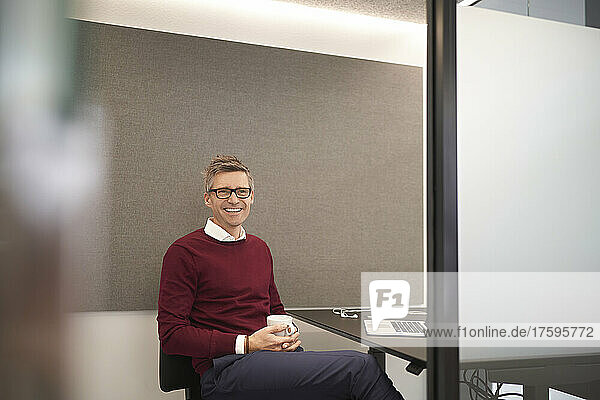 Smiling businessman with coffee cup at office