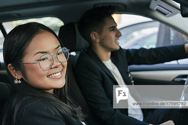 Lächelnde Geschäftsfrau mit Kollege beim Autofahren
