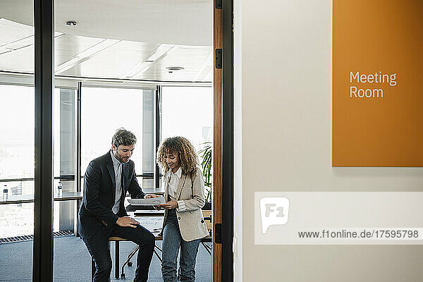 Businesswoman discussing with businessman over document in office