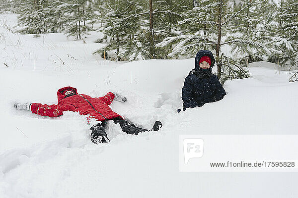 Twin brothers playing on snow in forest