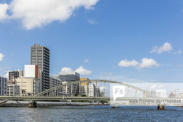 Japan  Kanto Region  Tokyo  Railway bridge stretching over Sumida River with apartment buildings in background