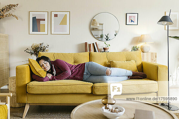Young woman sleeping on sofa in living room