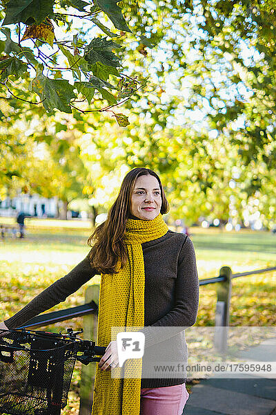 Beautiful woman wheeling bicycle at autumn park