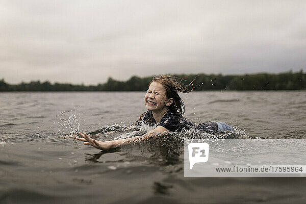 Happy girl with eyes closed swimming in lake