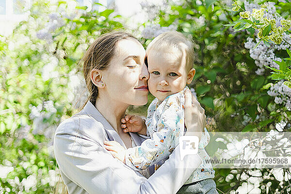 Mother with eyes closed embracing son in garden