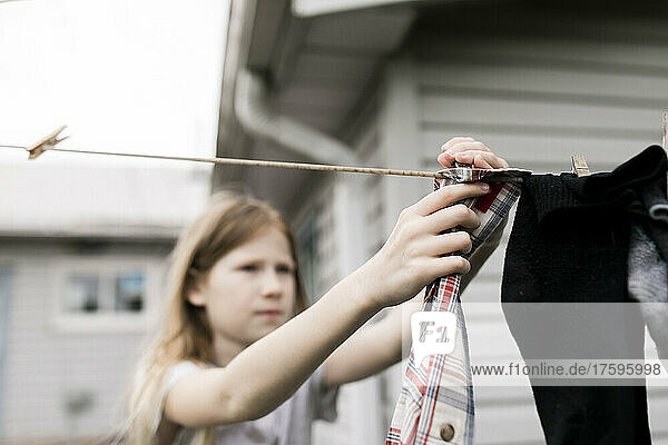 Mädchen hängt Kleidung an Seil