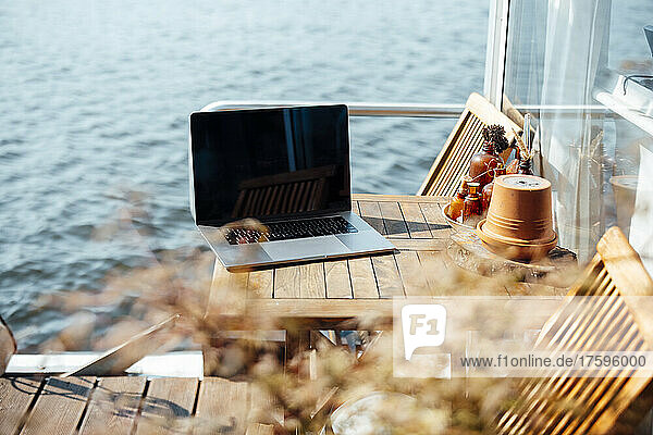 Laptop on wooden table at houseboat on sunny day