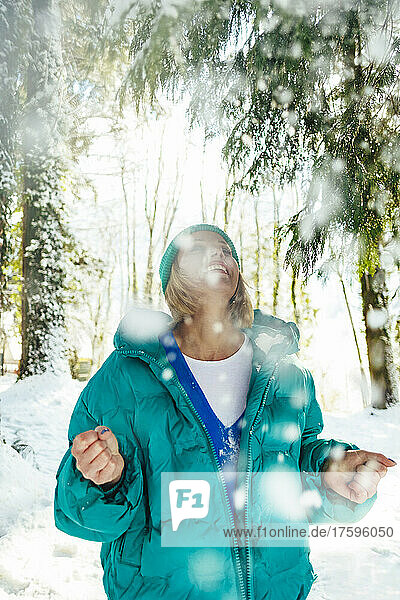 Happy woman enjoying snowfall in forest