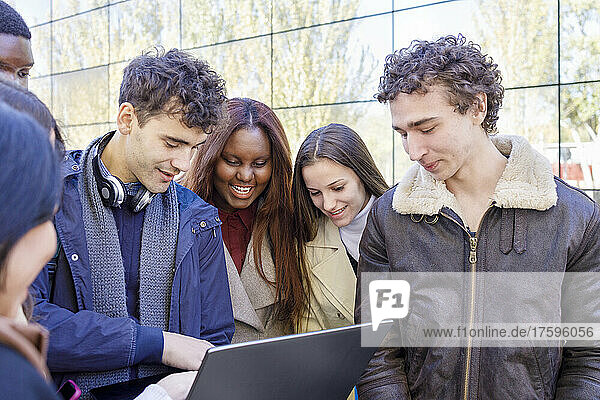 Students sharing laptop on university campus