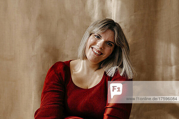 Happy curvy woman with blond hair in front of brown backdrop