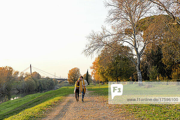 Paar geht gemeinsam auf Fußweg im Herbstpark spazieren