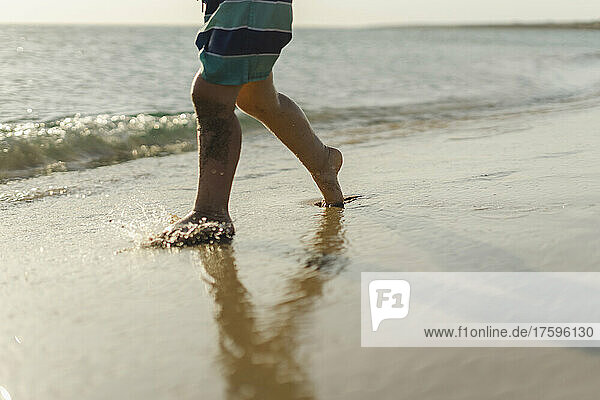 Boy walking on shore at beach