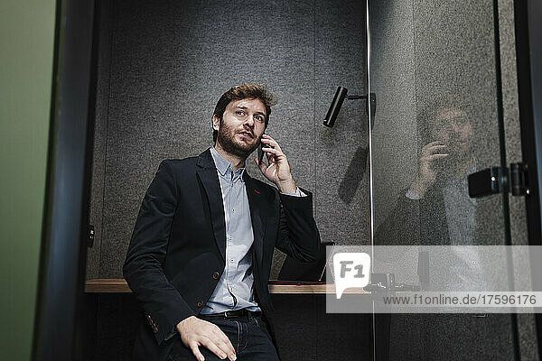 Businessman talking on smart phone sitting in cabin