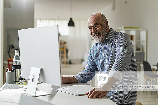 Cheerful senior freelancer with computer working from home