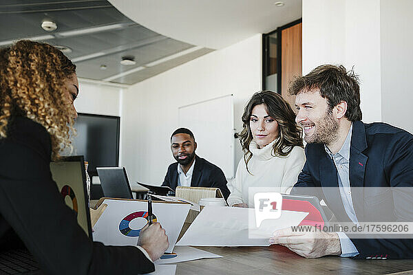 Smiling businessman discussing strategy with colleagues in office