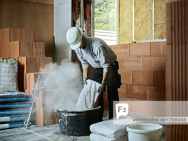 Bricklayer putting cement in tub at construction site