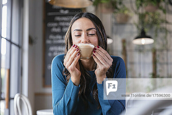 Happy woman drinking cappuccino in coffee shop