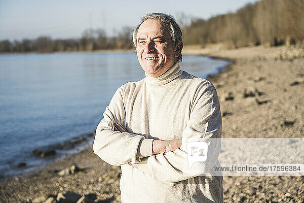 Smiling man standing with arms crossed on sunny day