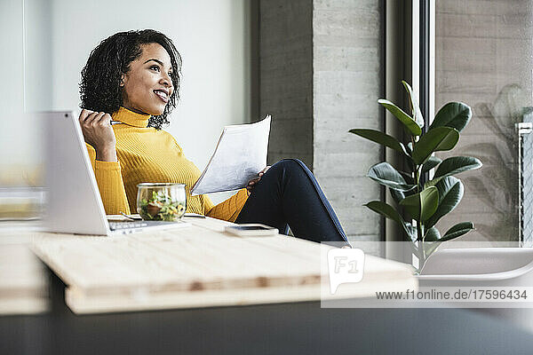 Thoughtful businesswoman with document in office